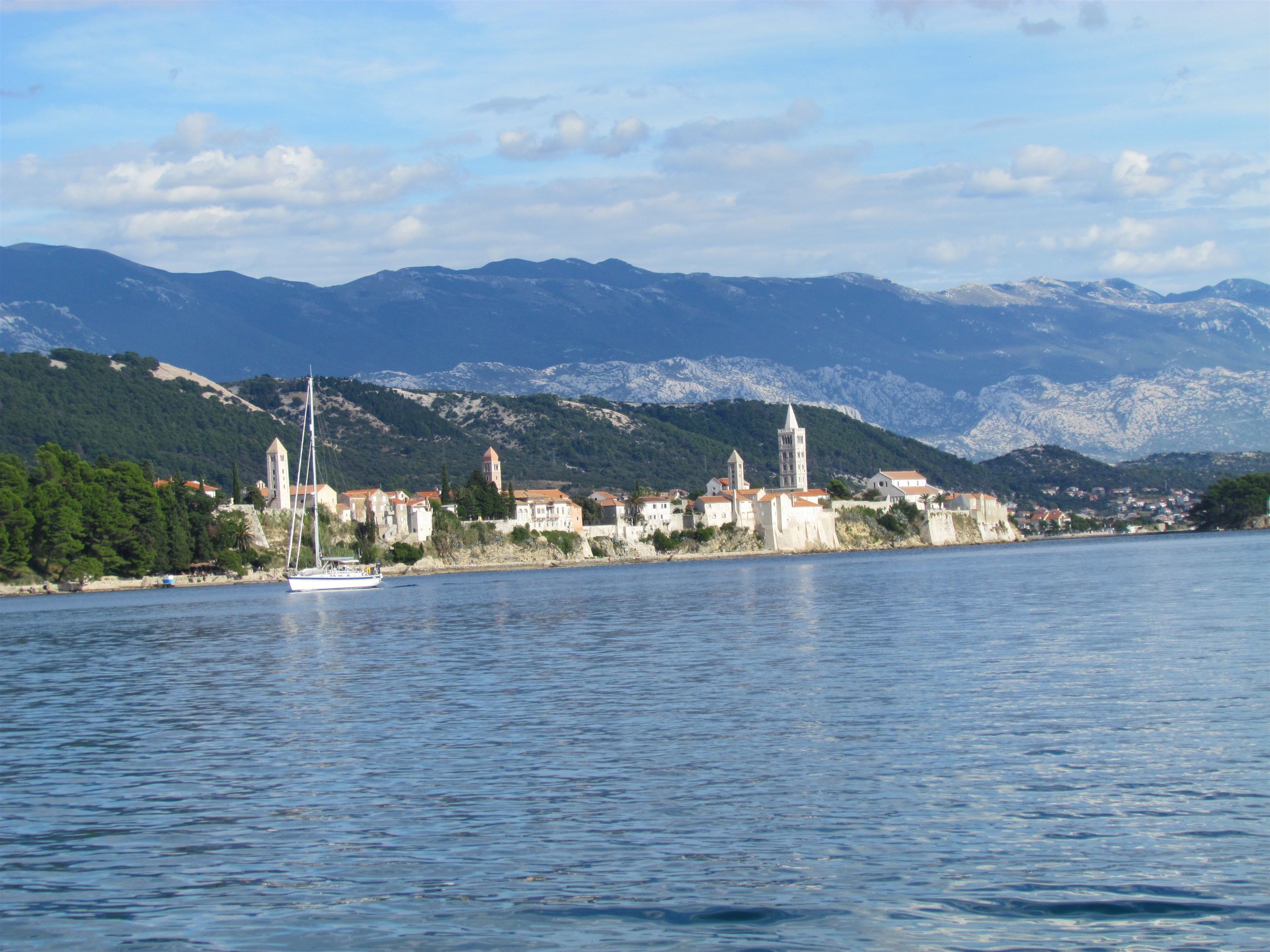 A coastal town with a prominent church and a sailboat on the water.