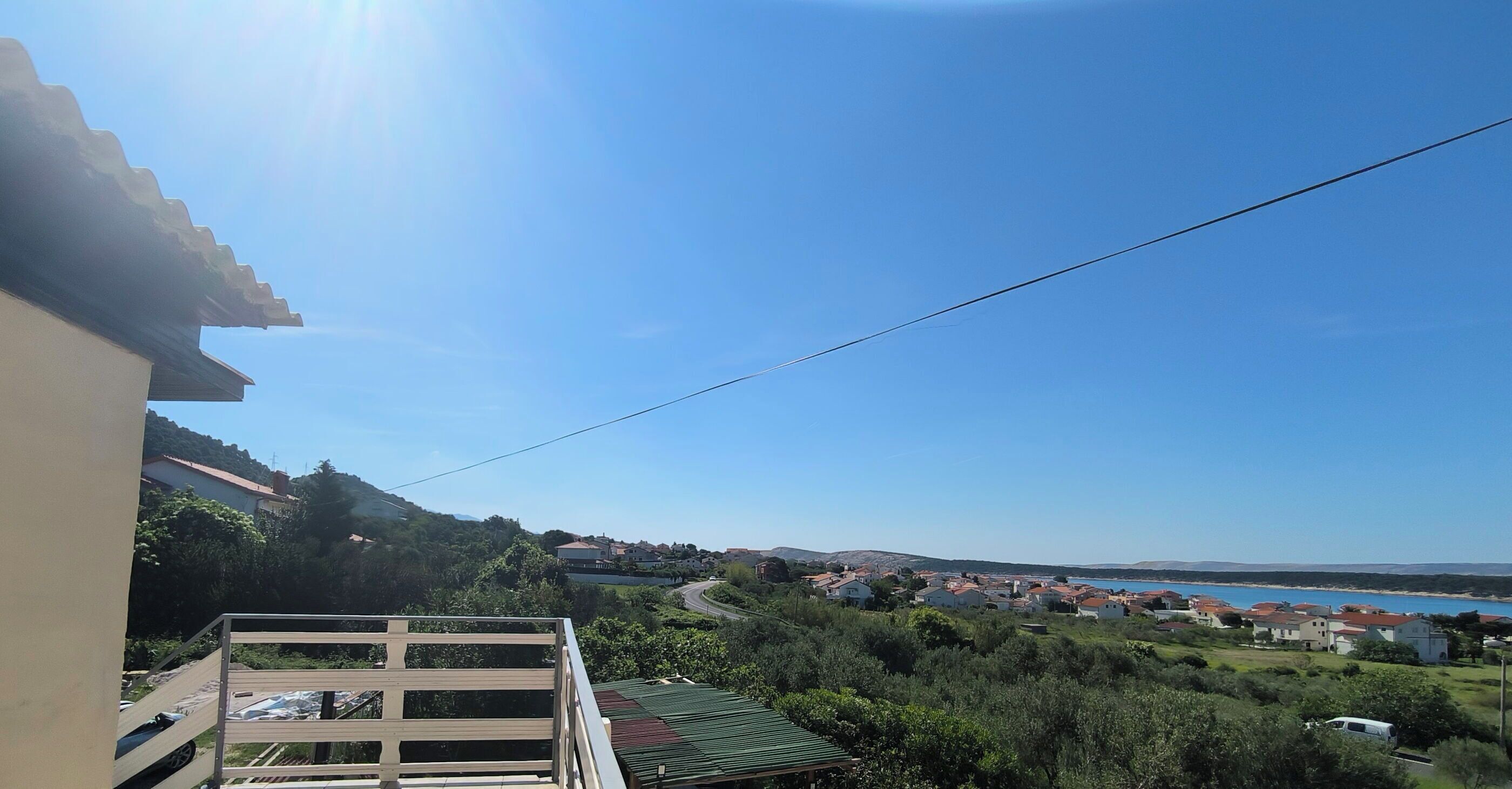 A residential area with houses, a road, and a body of water in the distance.