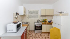 Eine kleine Küche mit Mikrowelle, Herd, Spüle und Kühlschrank.