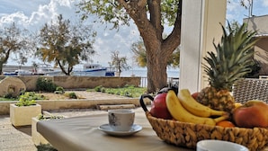 A table with a fruit bowl and a cup, overlooking a marina with boats.