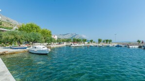 A marina with boats docked, clear water, and a mountainous backdrop.