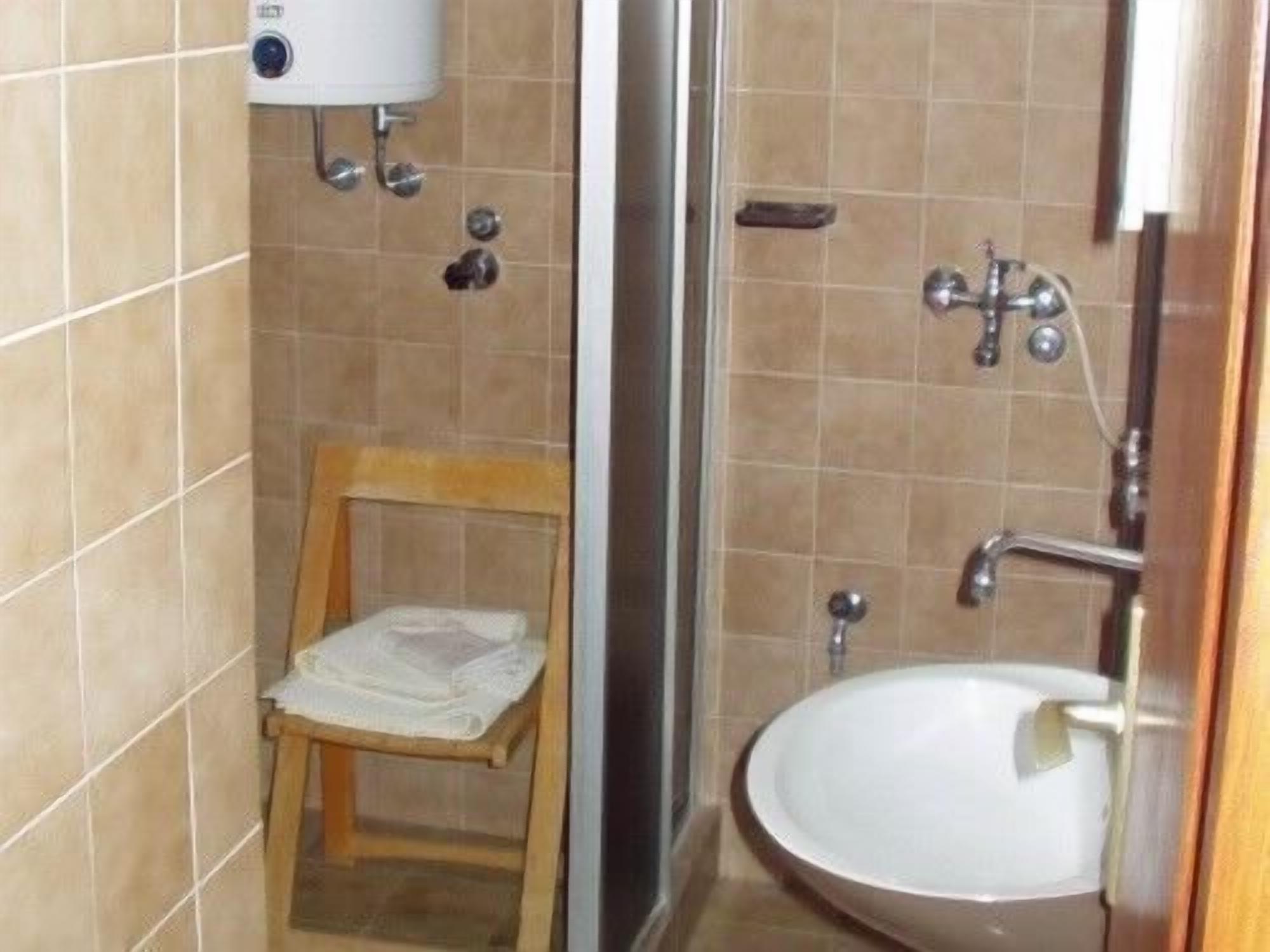 Une salle de bain avec une chaise en bois, un lavabo blanc et un espace douche.