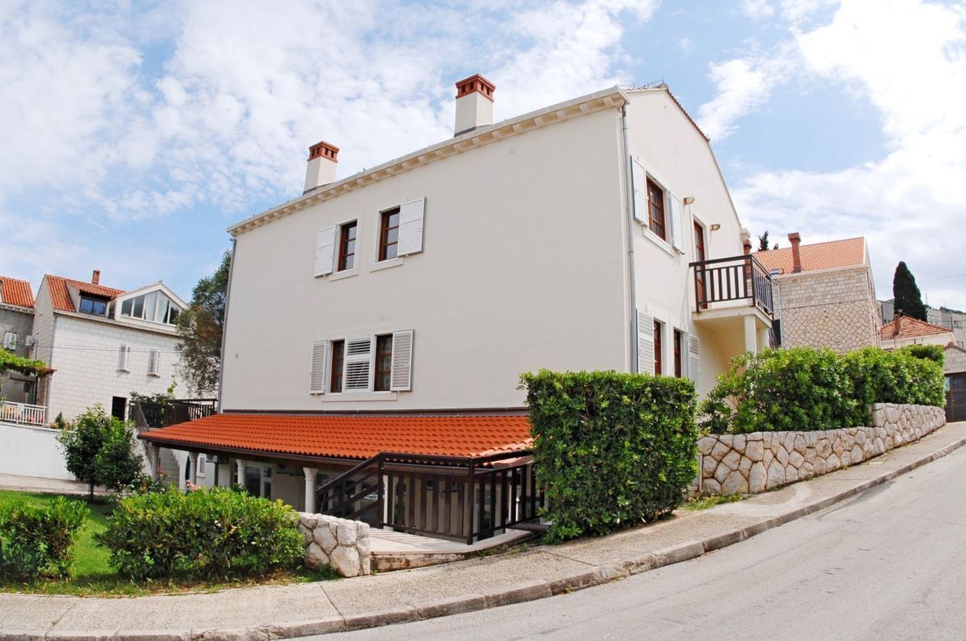 A two-story building with a red-tiled roof, white walls, and a balcony.