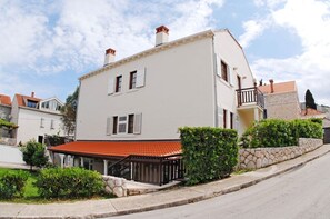 Um edifício de dois andares com telhado de telhas vermelhas, paredes brancas e uma varanda.