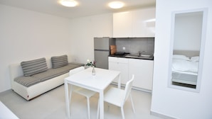 Ett kompakt bostadsutrymme med en soffa, ett matbord och ett litet kök.