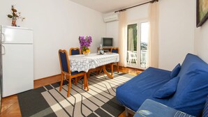 Un espace de vie compact comprenant une table à manger, des chaises, un canapé, un téléviseur et un réfrigérateur.