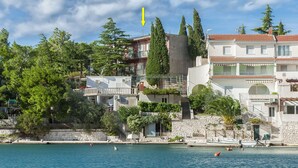 Un bâtiment situé sur la côte, doté de balcons, d’un mur en pierre et d’un drapeau.
