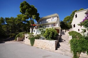 A two-story building with a balcony, surrounded by greenery and a clear sky. - Apartments Marjan (Smokvica)