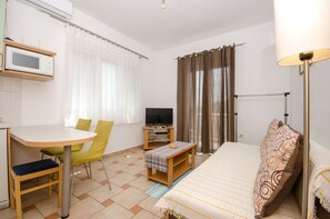 A compact room with a bed, a television, a small table with a chair, and a microwave. - Apartments Marjan (Smokvica)