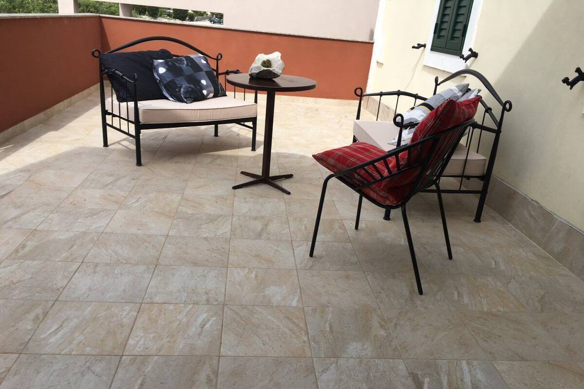 A patio with a sofa and a chair, a small round table, and a decorative rock.