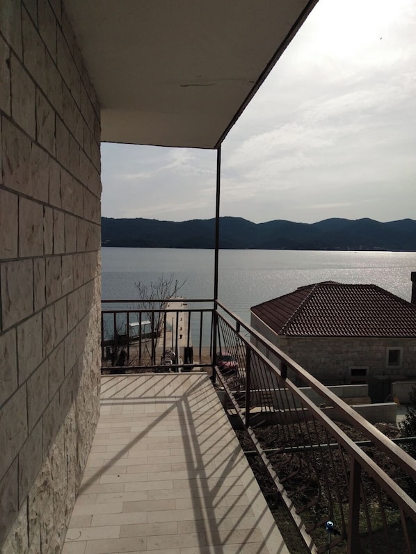 A balcony with a view of a lake and distant mountains.