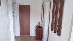 Een gang met houten vloeren, een houten dressoir en een deur aan het einde.