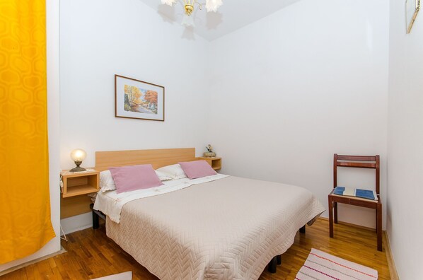 A neatly arranged bedroom with a bed, bedside table, lamp, and a chair. - Apartment Jasenka (Brna)