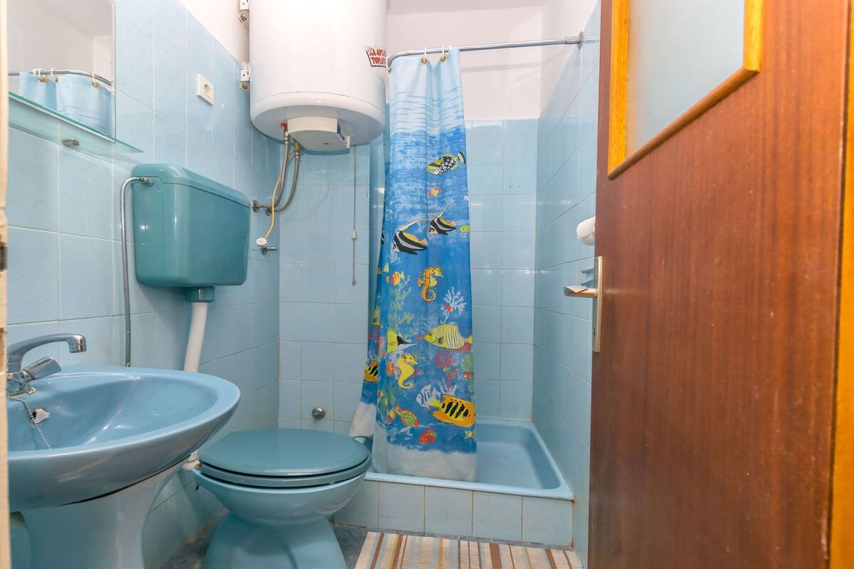Een badkamer met toilet, wastafel, douchegordijn met zeedieren en een toiletrolhouder.
