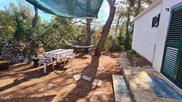 A patio with a table and chairs, a hammock, and a stone wall.