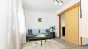A modern living room with a sofa, a small round table, a potted plant, and a sliding door. - Apartment Ivan (Lumbarda)