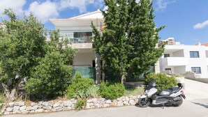 A modern two-story house with a stone wall and a parked scooter in front. - Apartments Ksenija (Primosten)