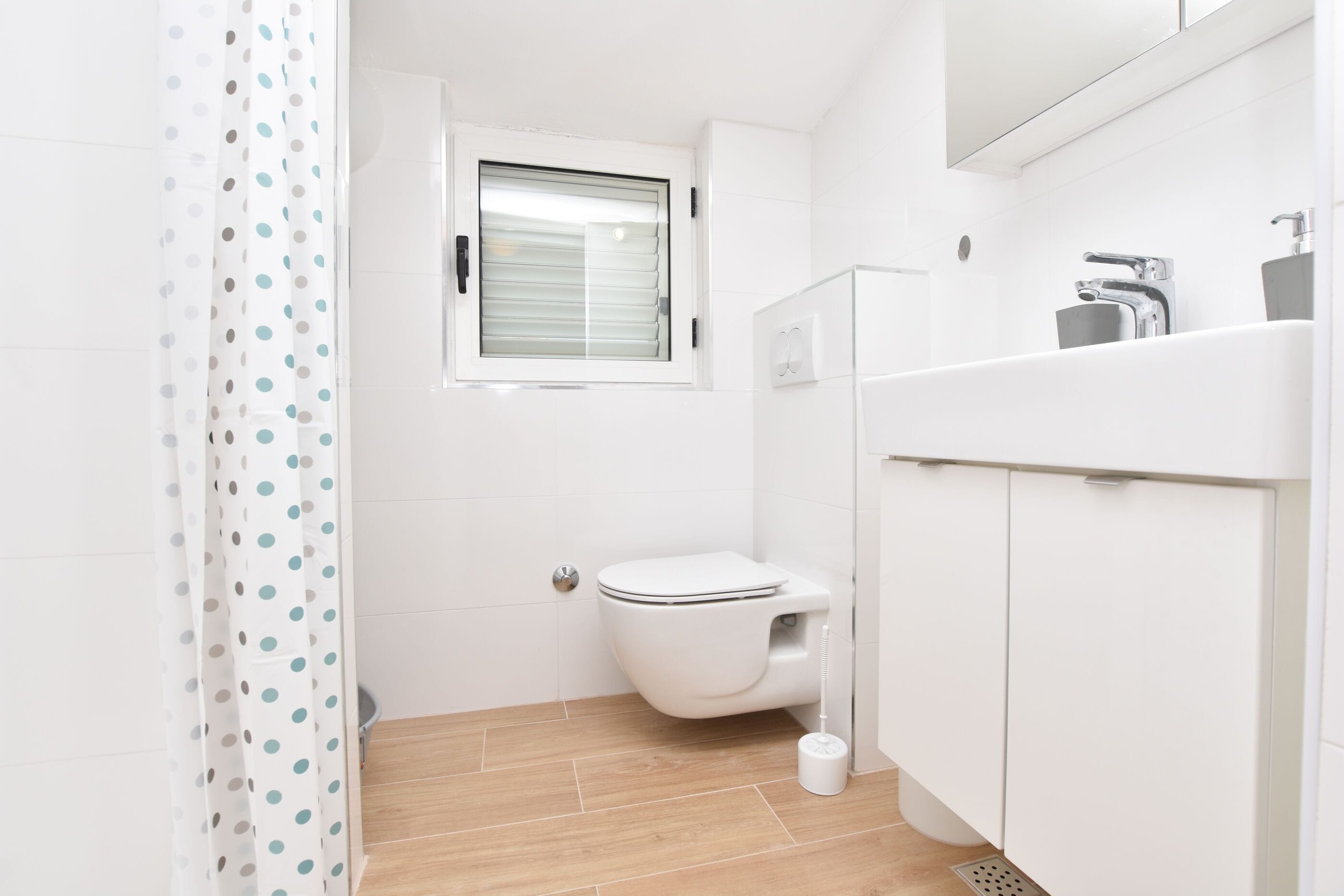 Ein kleines, modernes Badezimmer mit Toilette, Fenster und Duschvorhang.