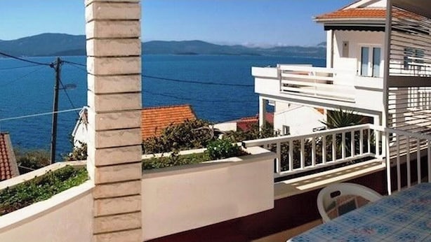 Ein Balkon mit Blick auf das Meer und die Berge.