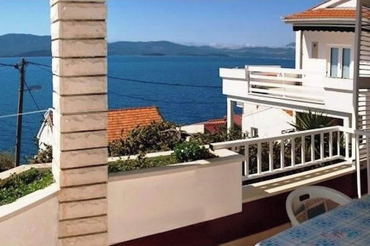 A balcony with a view of the sea and mountains.