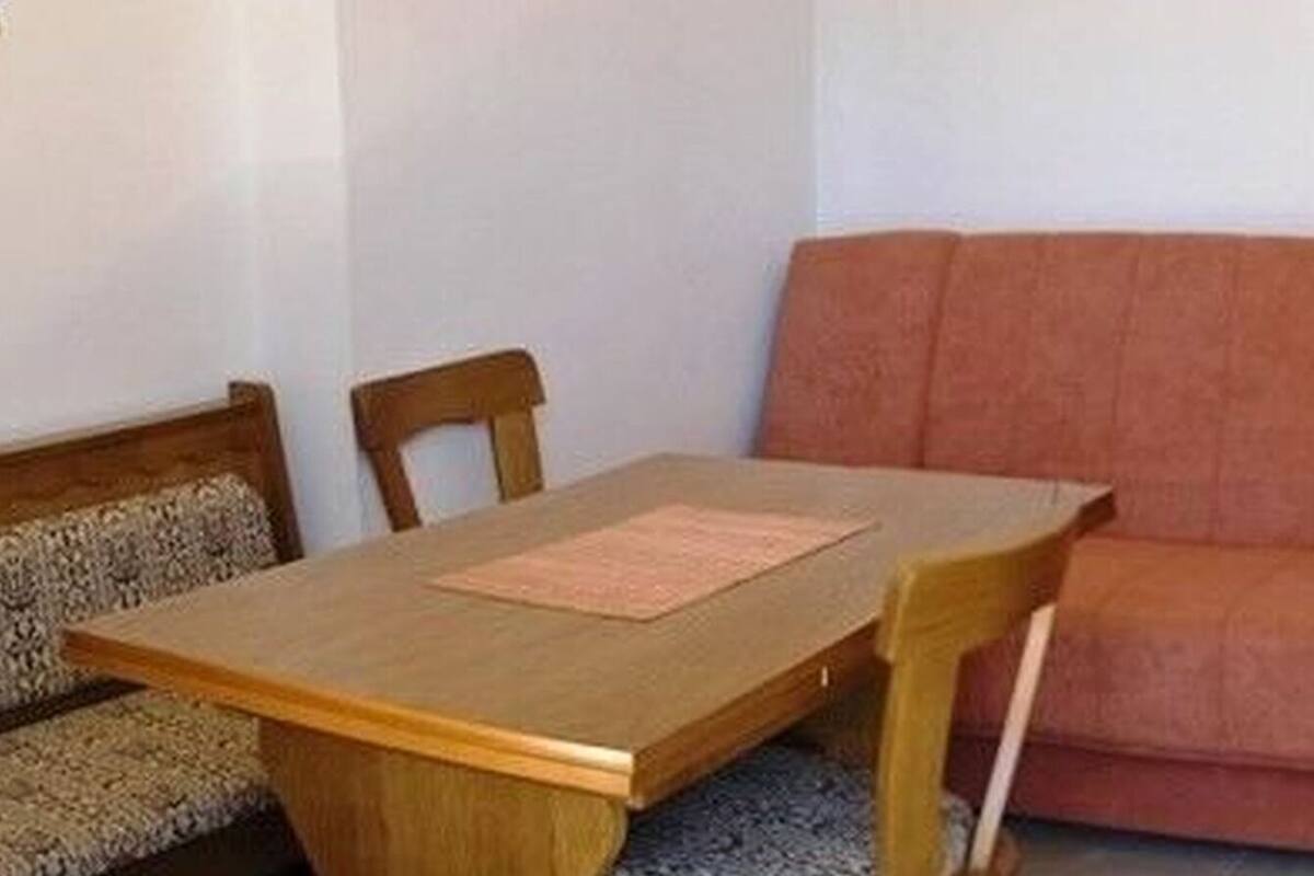 A room with a wooden dining table, two chairs, and a red sofa.