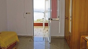 Ein Zimmer mit einem Bett, einem Holzschrank und einer Tür, die auf einen Balkon führt.