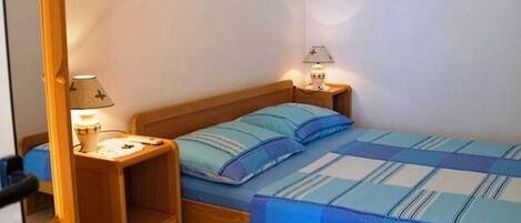 A small, single-bed room with a wooden headboard and two bedside tables, each with a lamp.
