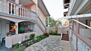A courtyard with a stone pathway, a balcony with white balustrades, and potted plants. - Apartments Kralj (Privlaka)