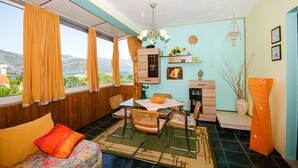 A room with a dining table, chairs, a sofa, and a view of the outdoors. - Apartment Slavka (Kneza)