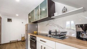 A modern kitchen with a marble backsplash, stainless steel appliances, and a wooden countertop. - 2 bedroom cozy apartment in Ogulin (Ogulin)