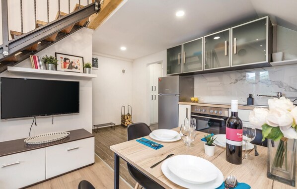 A modern kitchen with a built-in oven, a refrigerator, and a dining area with a table set for two. - 2 bedroom cozy apartment in Ogulin (Ogulin)