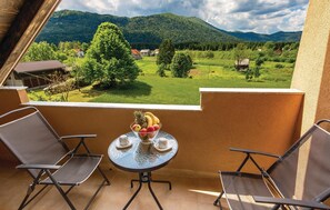 Enjoy a serene view of the surrounding landscape from this balcony, featuring a comfortable seating area with a table and amenities.