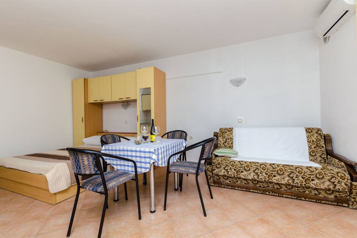 Ein gemütlicher Raum mit einem Bett, einem Esstisch mit Stühlen, einer Couch und einer kleinen Küchenzeile.