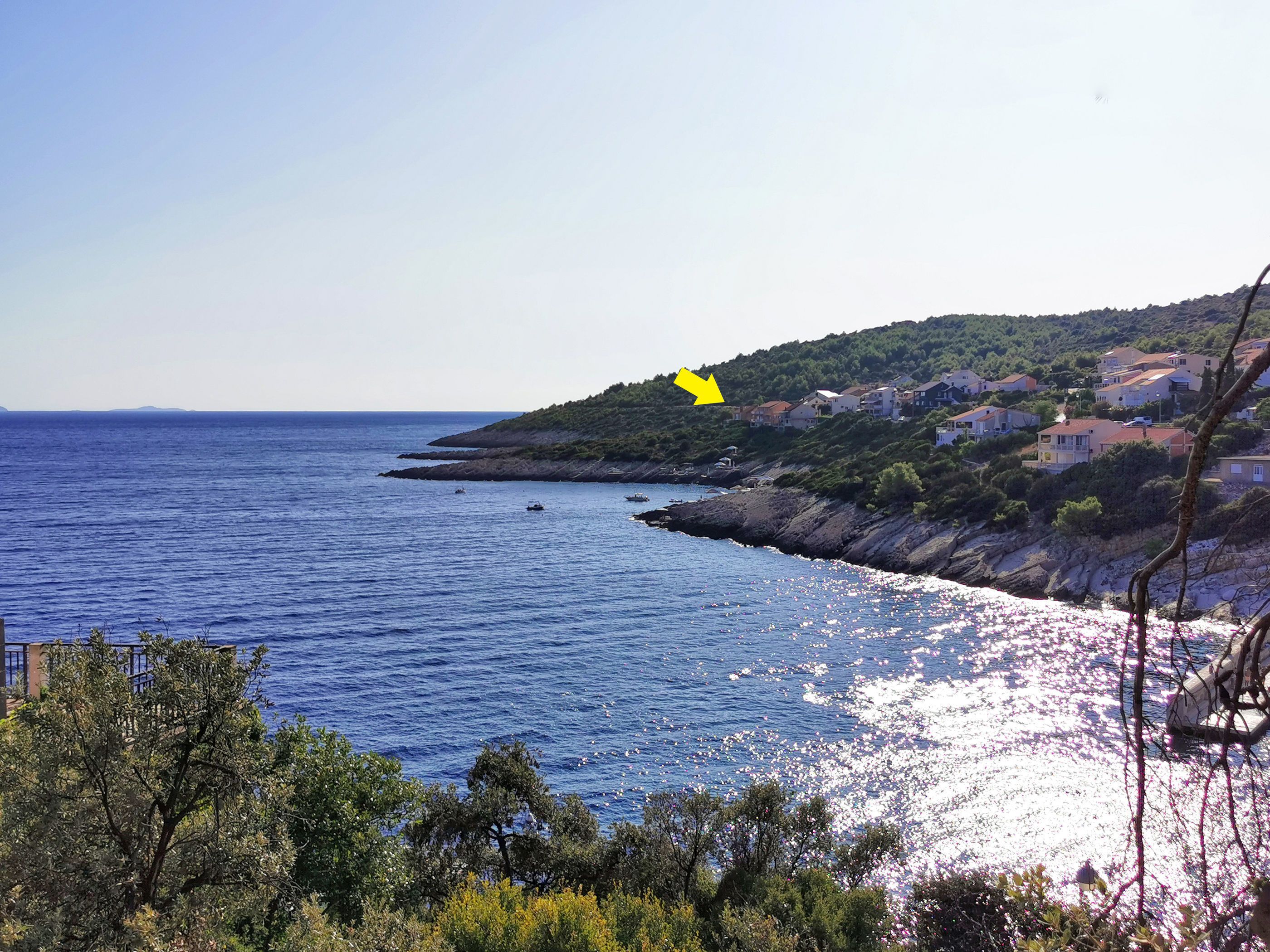 Vista costera con costa rocosa, un pequeño pueblo con casas y barcos en el agua.