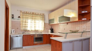 Une cuisine moderne avec des meubles en bois, un lave-vaisselle, une cuisinière et une table basse en verre.
