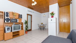 Un espacio habitable compacto con kitchenette, muebles de madera, una zona de comedor y una cama.