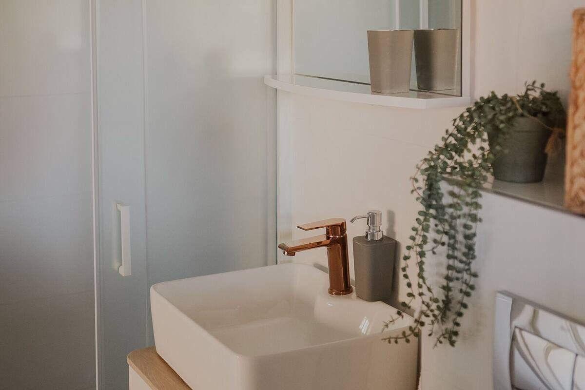 A modern bathroom with a white sink, a mirror, and a shower.