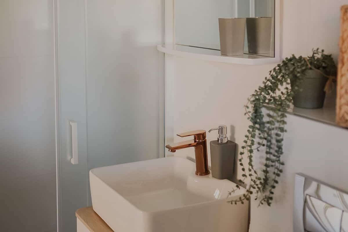 A modern bathroom with a white sink, a mirror, and a shower.
