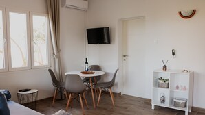 A modern living room with a dining area, a TV mounted on the wall, and a white cabinet with shelves. - Apartments Prce (Orebic)