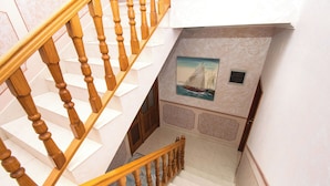 Un escalier avec des balustrades en bois et un mur blanc orné d’un tableau représentant un voilier.