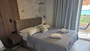 Une chambre d’hôtel moderne, équipée d’un lit, d’une table de chevet, d’une chaise et offrant une vue sur la mer.