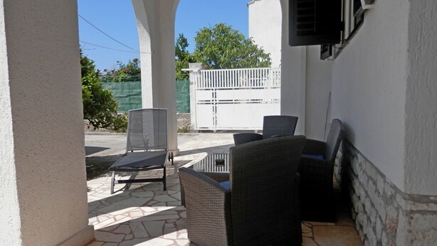 Un patio al aire libre con suelo de piedra, una mesa y dos sillas.