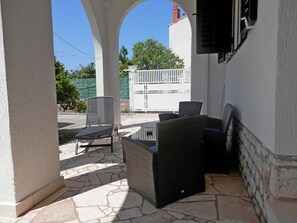 An outdoor patio area with stone flooring, a table, and two chairs. - Apartments Zivana (Rogoznica)