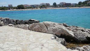 Una zona costera con terreno rocoso y un mar azul cristalino.