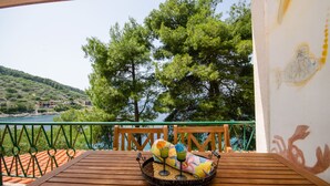 A wooden table with a tray of drinks and a colorful towel on a balcony overlooking a body of water and trees. - Apartment Dijana (Crnja Luka)