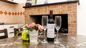 A table with a bottle of wine, two glasses, and a vase with flowers. - Apartment Dijana (Crnja Luka)