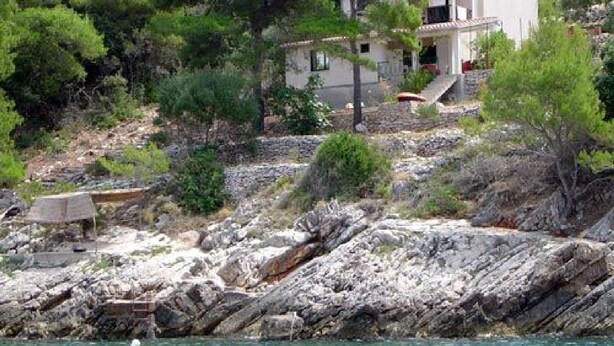 A coastal property with a white building, a small staircase, and a rocky shoreline. - Apartment Dijana (Crnja Luka)