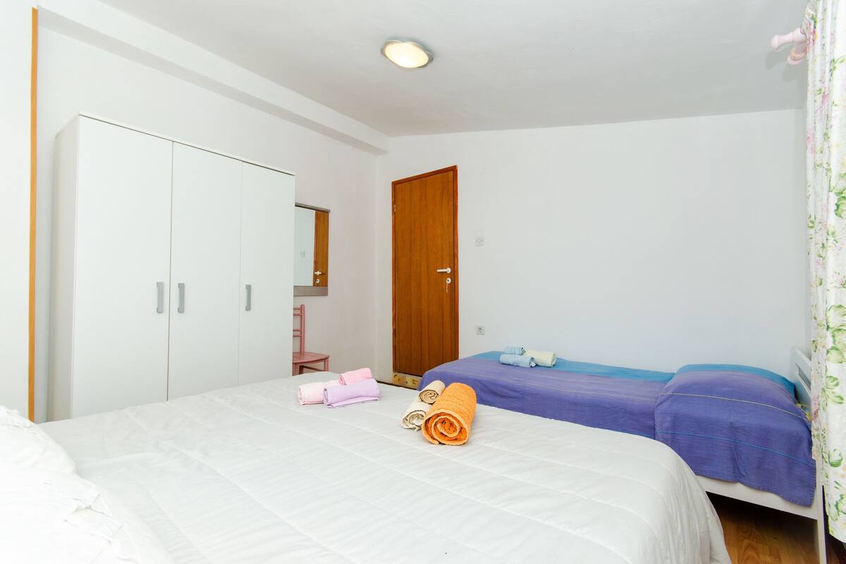 A bedroom with a bed, two bedside tables, a wardrobe, and a door.
