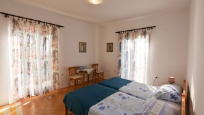 Une chambre avec deux lits, un bureau, des chaises et des rideaux.