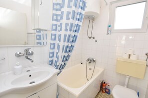 A bathroom with a bathtub, a sink, a toilet, and a shower. - Apartment Vlasta (Primosten)